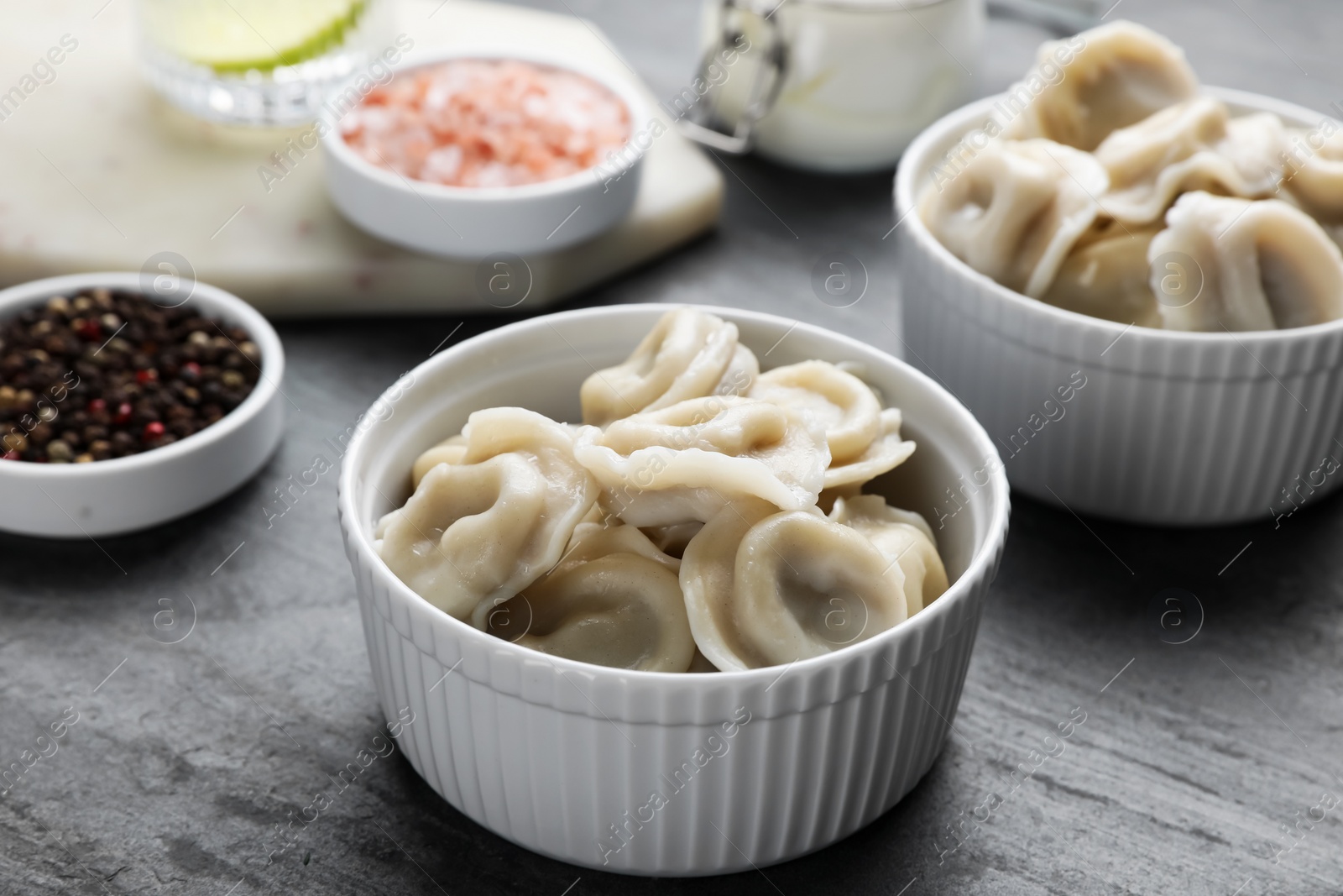 Photo of Tasty dumplings in bowls served on grey table