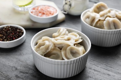 Photo of Tasty dumplings in bowls served on grey table