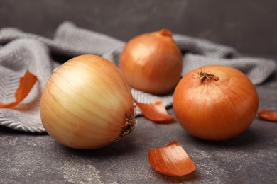 Photo of Ripe onions on grey stone table, closeup