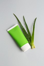 Tube of toothpaste and fresh aloe on light grey background, flat lay