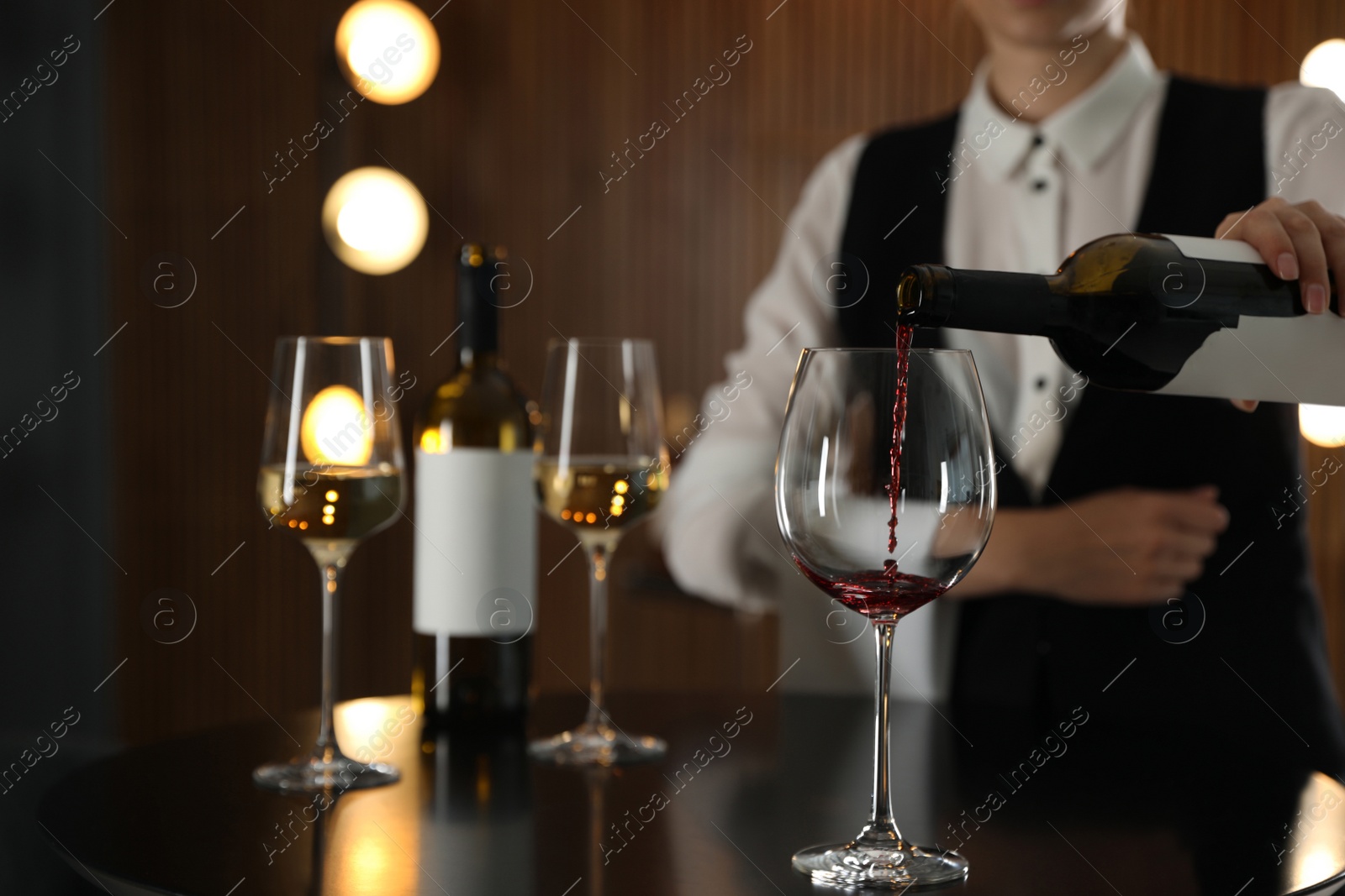 Photo of Waitress pouring wine into glass in restaurant, closeup