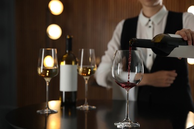 Photo of Waitress pouring wine into glass in restaurant, closeup