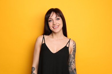 Photo of Beautiful woman with tattoos on arms against yellow background