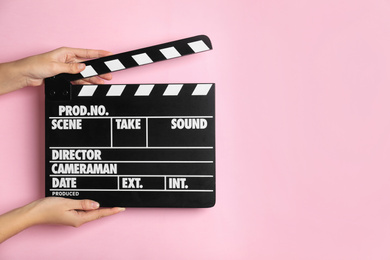 Photo of Woman holding clapperboard on pink background, closeup with space for text. Cinema production