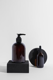 Photo of Bottles with different cosmetic products and podiums on white background