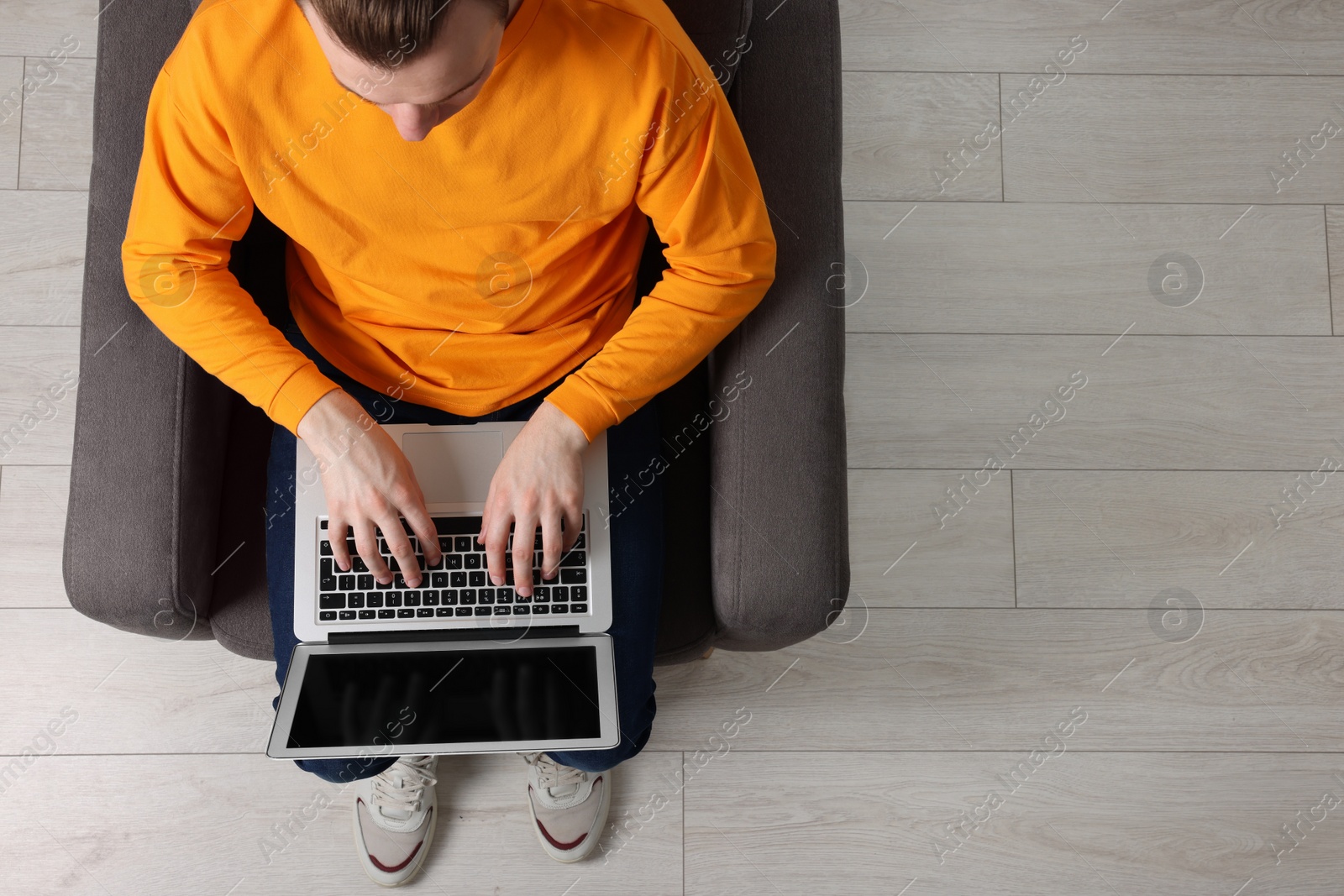 Photo of Man working with laptop in armchair, top view. Space for text