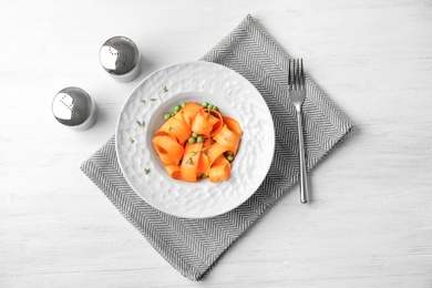 Photo of Tasty salad with fresh carrot in plate on table, top view