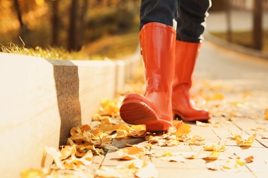 Woman wearing red rubber boots walking in autumn park, closeup