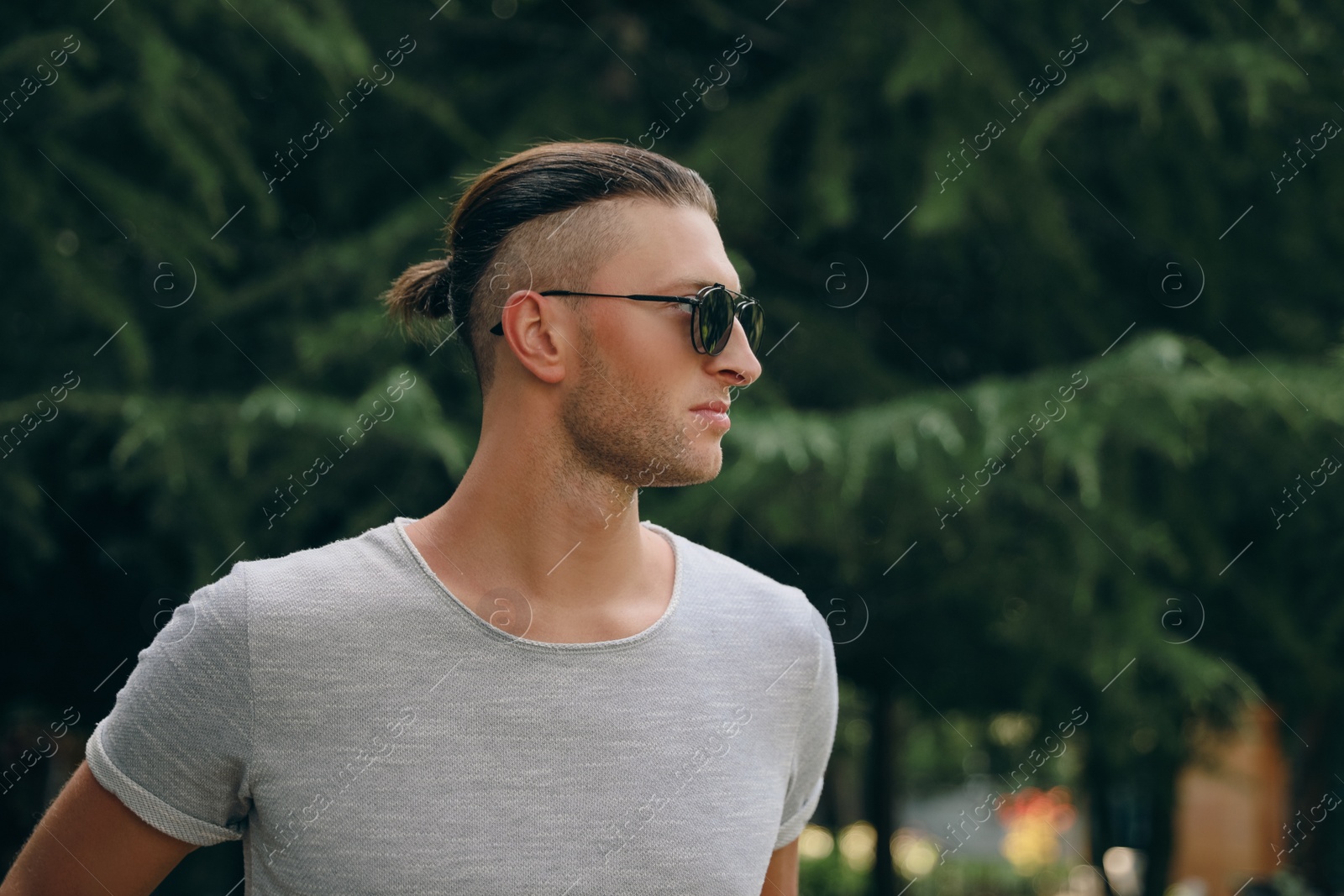 Photo of Handsome young man in stylish sunglasses at park, space for text