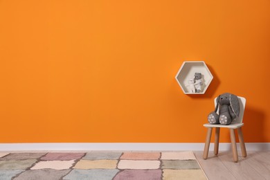 Beautiful children's room with bright orange wall and furniture, space for text. Interior design