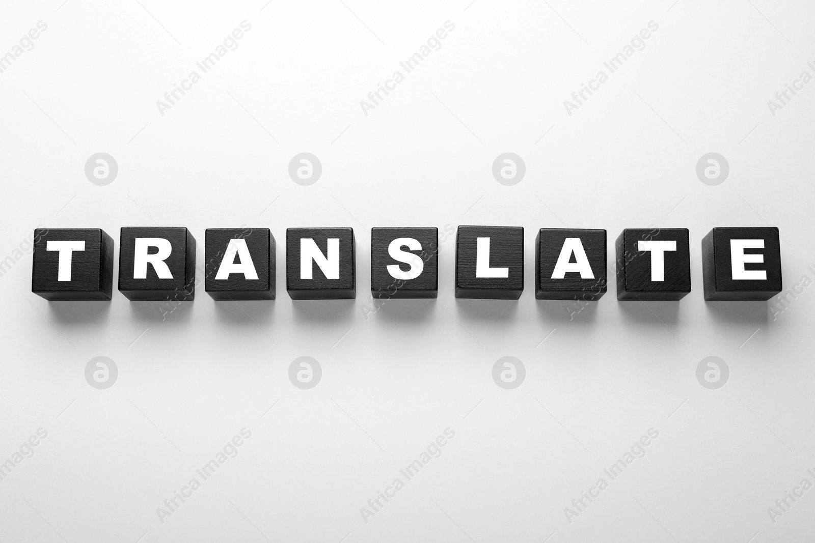 Photo of Black cubes with word Translate on white background, top view