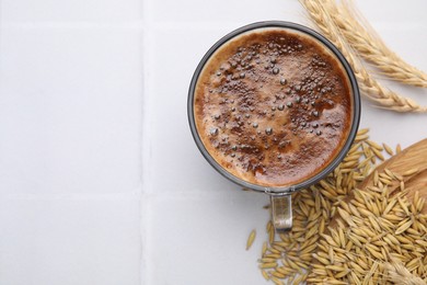 Photo of Cup of barley coffee, grains and spikes on white table, flat lay. Space for text