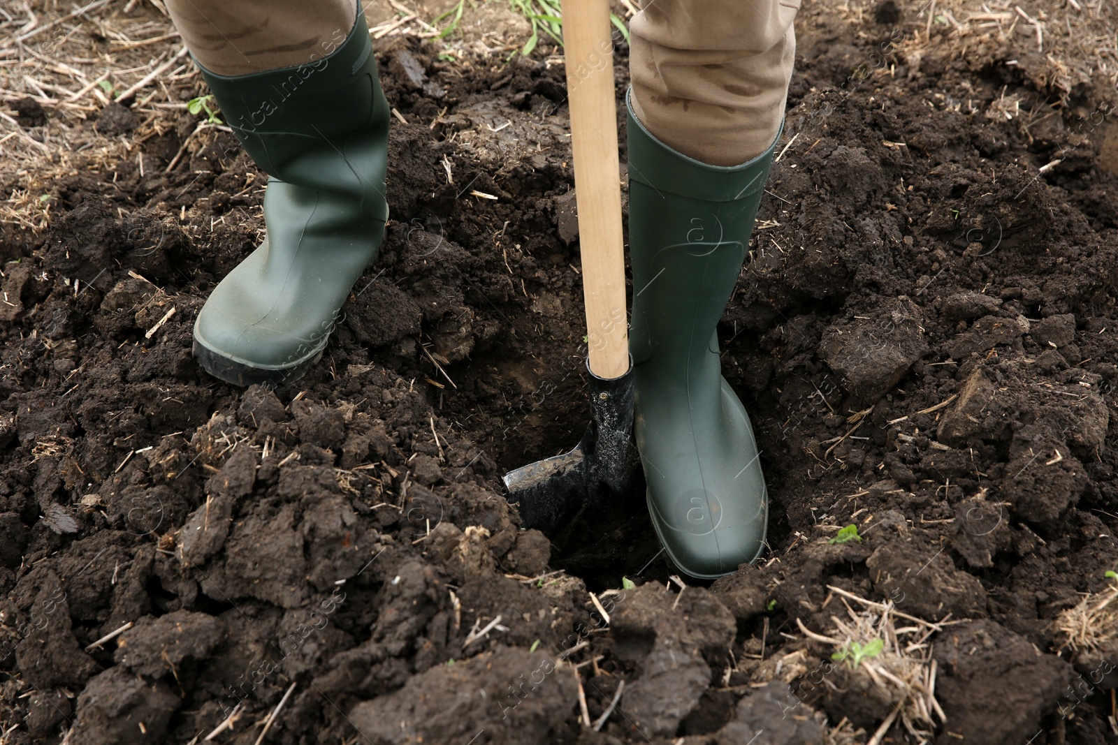 Photo of Worker digging soil with shovel outdoors, closeup