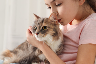 Photo of Cute little girl with cat at home, closeup. First pet