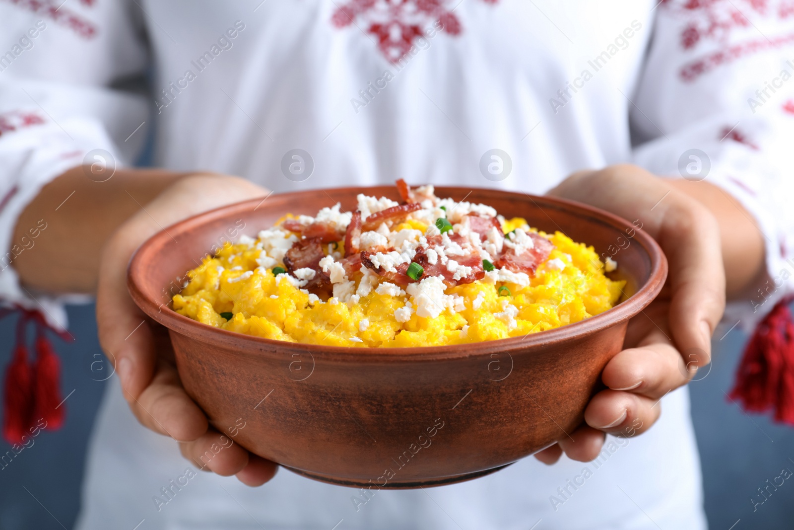 Photo of Woman holding bowl of banosh with brynza and pork cracklings, closeup. Traditional Ukrainian dish