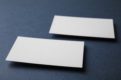 Blank business cards on dark grey background, closeup. Mock up for design