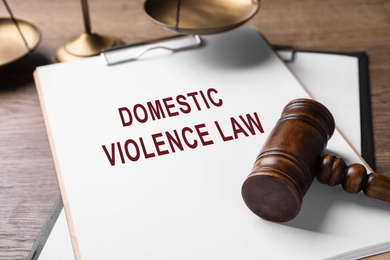 Image of Clipboard with words DOMESTIC VIOLENCE LAW and gavel on wooden table