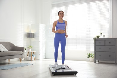 Photo of Sporty woman training on walking treadmill at home