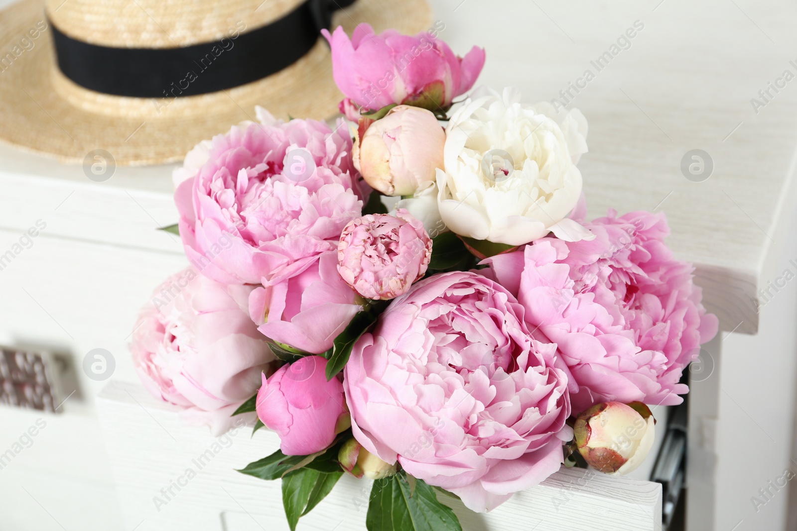 Photo of Bouquet of beautiful peonies in commode drawer indoors