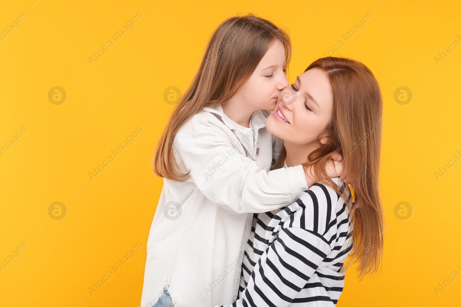 Photo of Portrait of happy mother and her cute daughter on orange background. Space for text