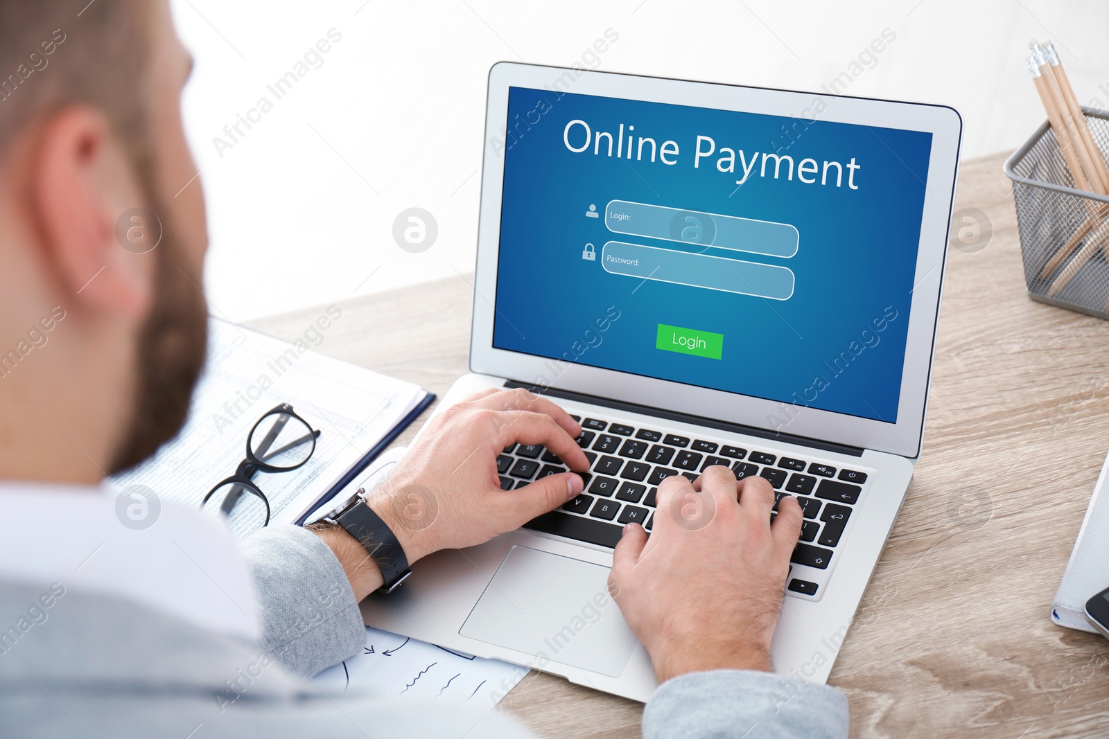 Image of Man using laptop for online payment at wooden table, closeup