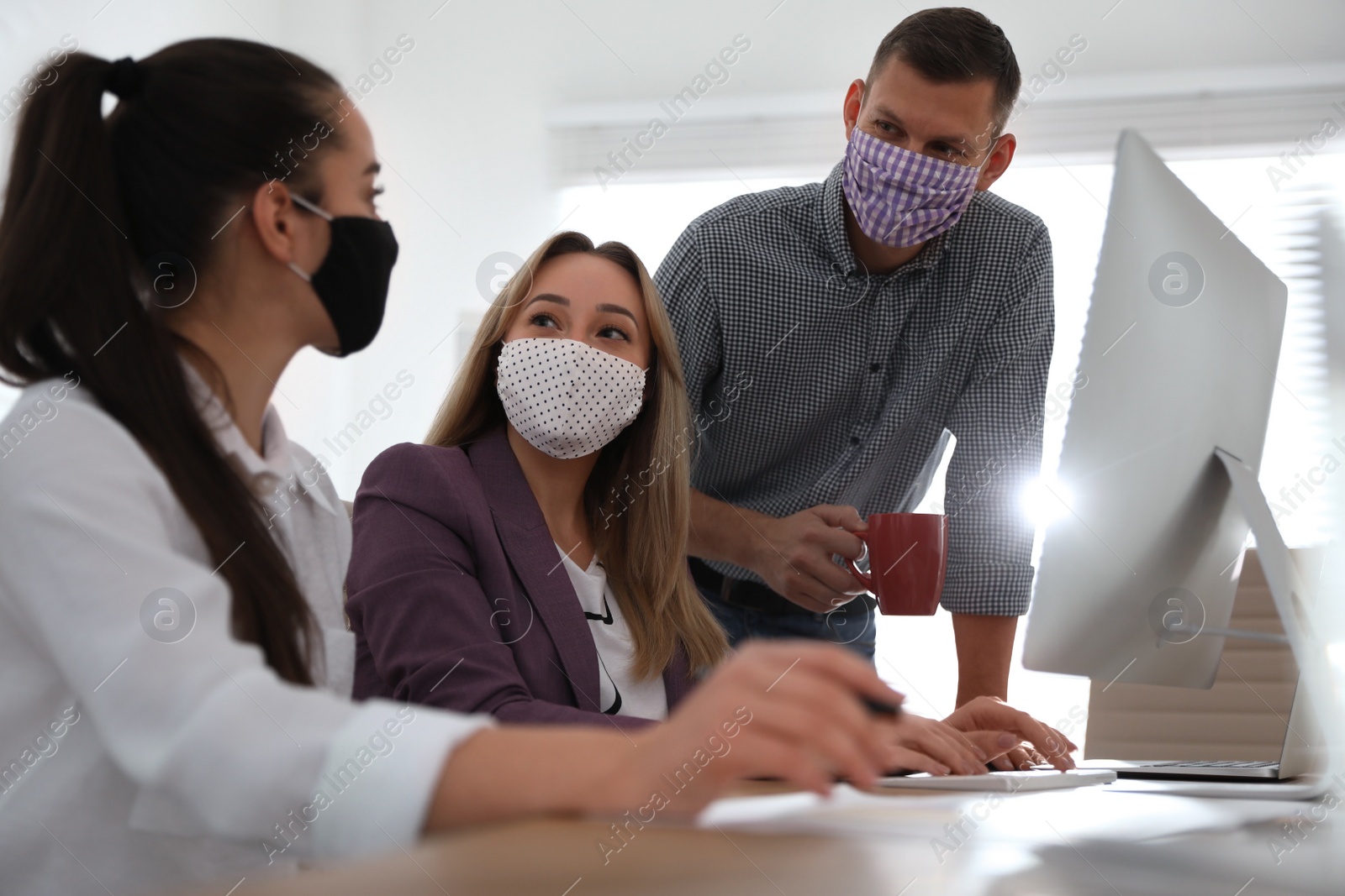 Photo of Coworkers with masks in office. Protective measure during COVID-19 pandemic