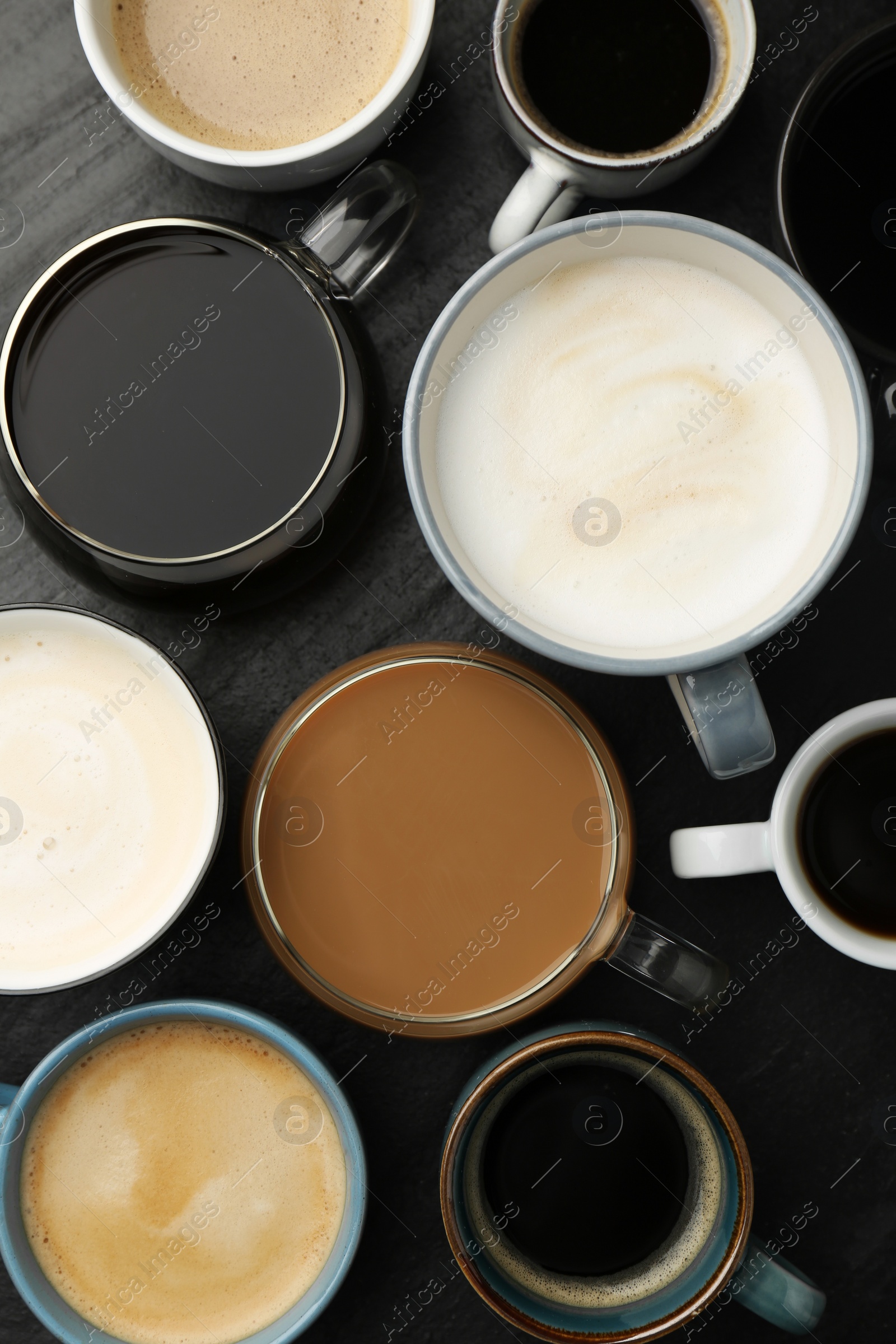 Photo of Different coffee drinks in cups on dark textured table, flat lay