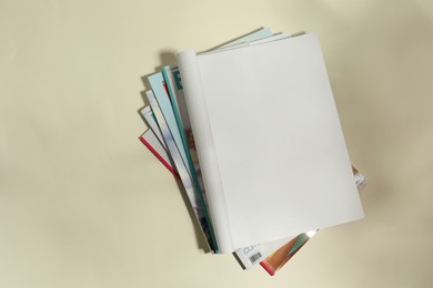 Photo of Stack of magazines and one open with blank page on beige background, top view