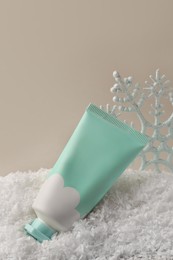 Photo of Winter skin care. Hand cream and decorative snowflake on artificial snow against light grey background