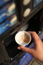 Photo of Woman taking paper cup with coffee from vending machine, above view
