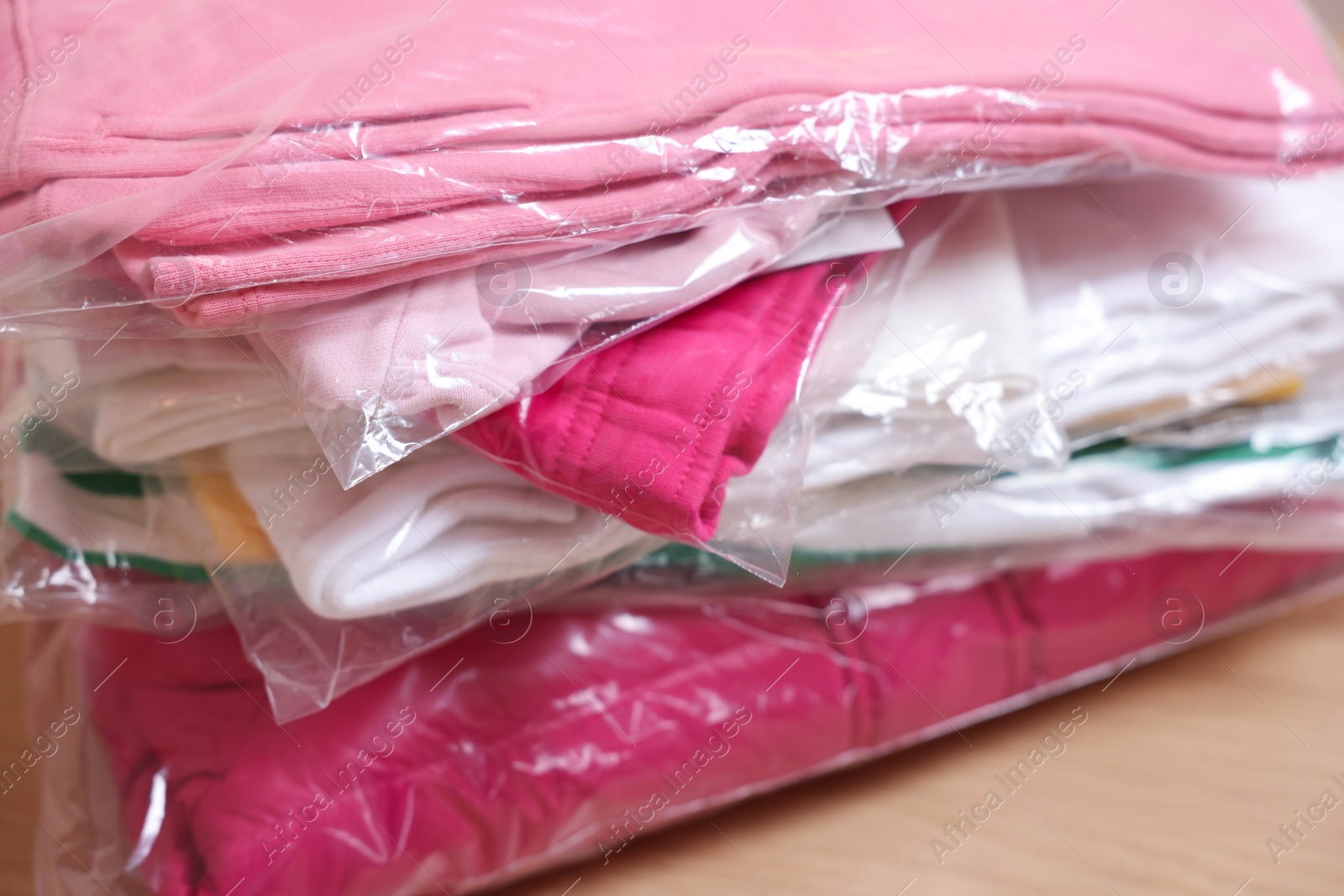 Stack of folded clothes in plastic bags on table, closeup Photo of Stack of folded clothes in plastic bags on table, closeup