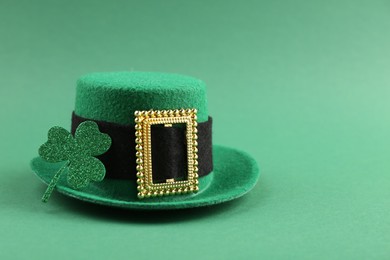 Photo of St. Patrick's day. Leprechaun hat and clover leaf on green background. Space for text