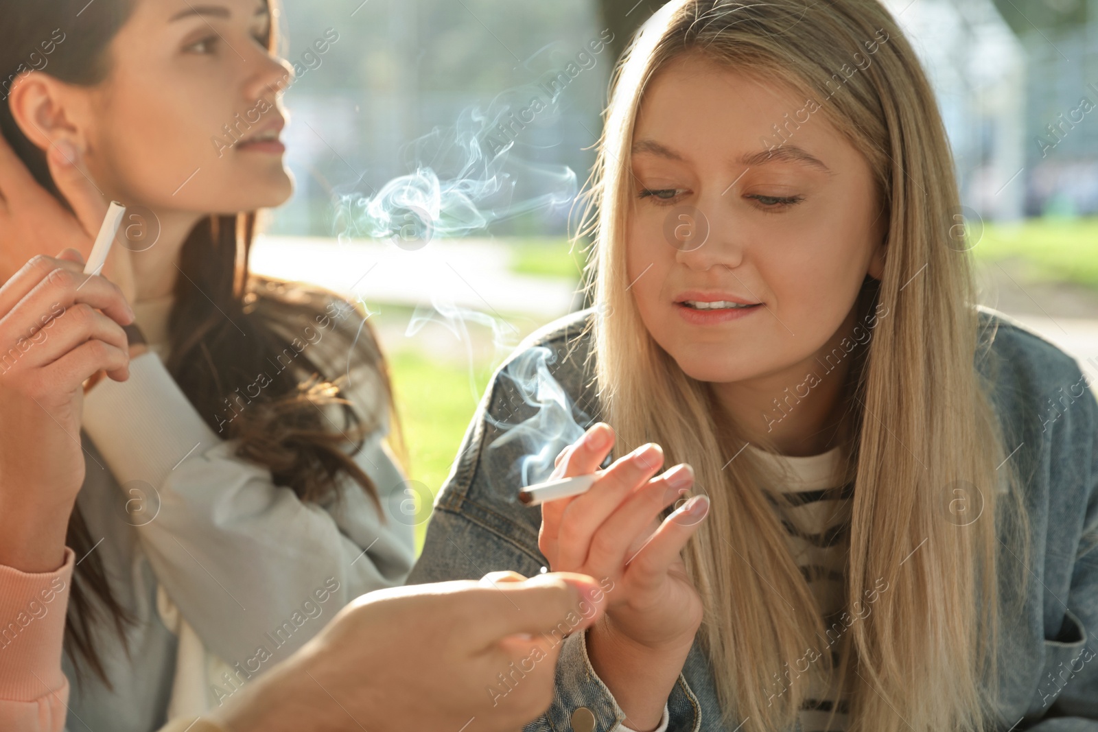 Photo of People smoking cigarettes outdoors on sunny day