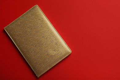 Photo of New stylish planner with leather cover on red background, top view. Space for text
