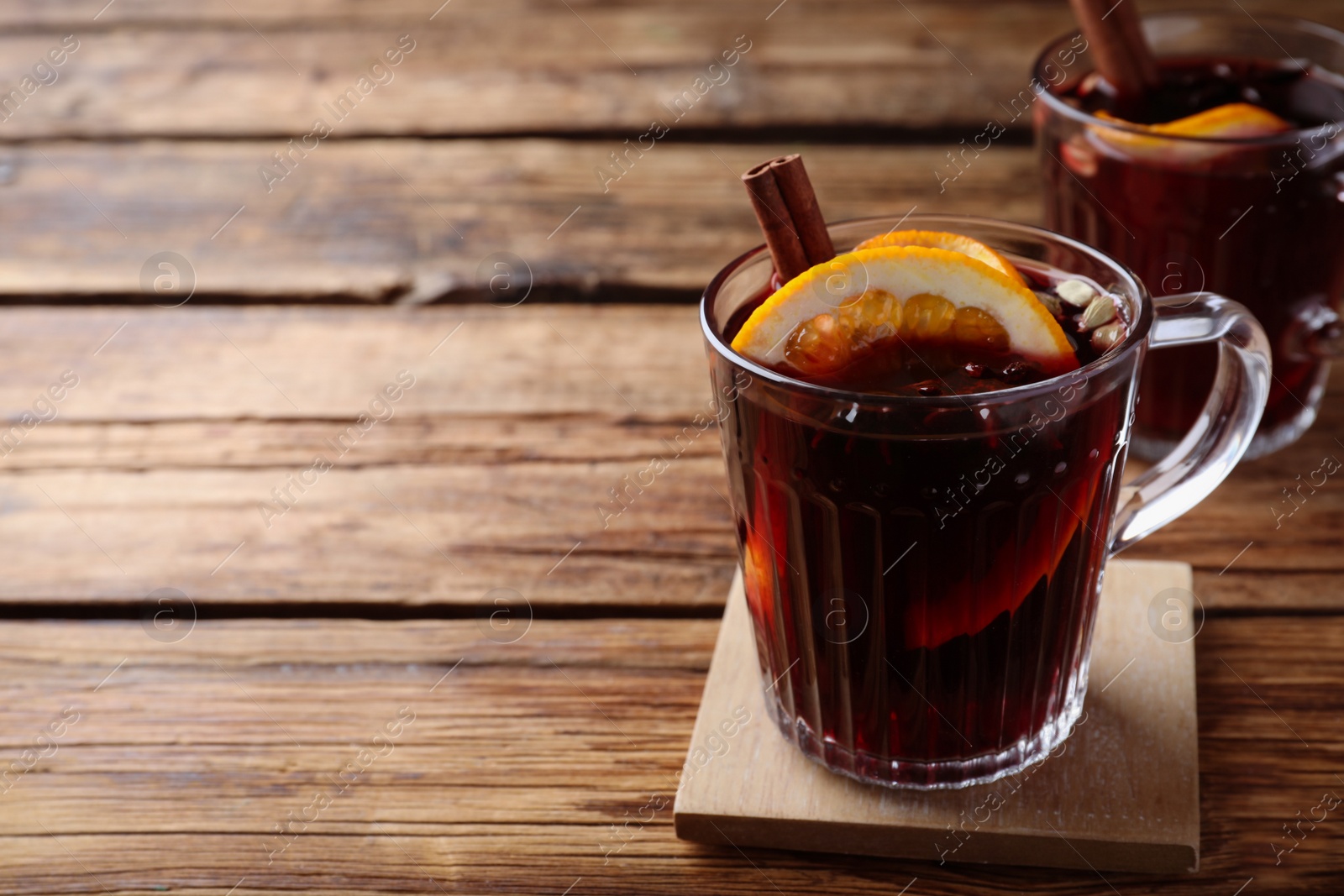 Photo of Aromatic mulled wine on wooden table, space for text