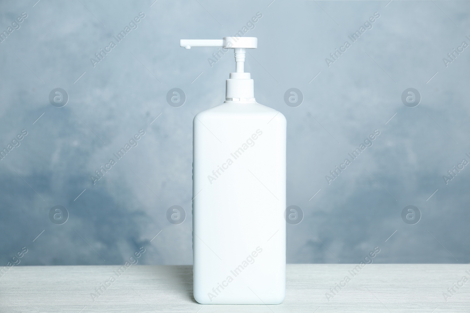 Photo of Dispenser bottle with antiseptic gel on table against light background