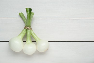 Photo of Bunch of green spring onions on white wooden table, flat lay. Space for text