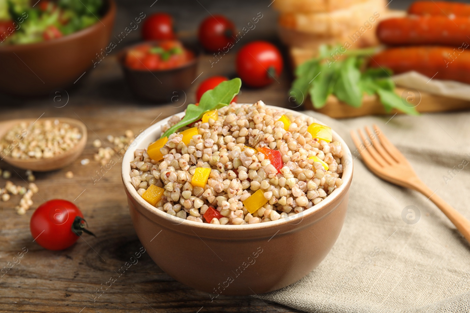 Photo of Tasty buckwheat porridge with vegetables on wooden table