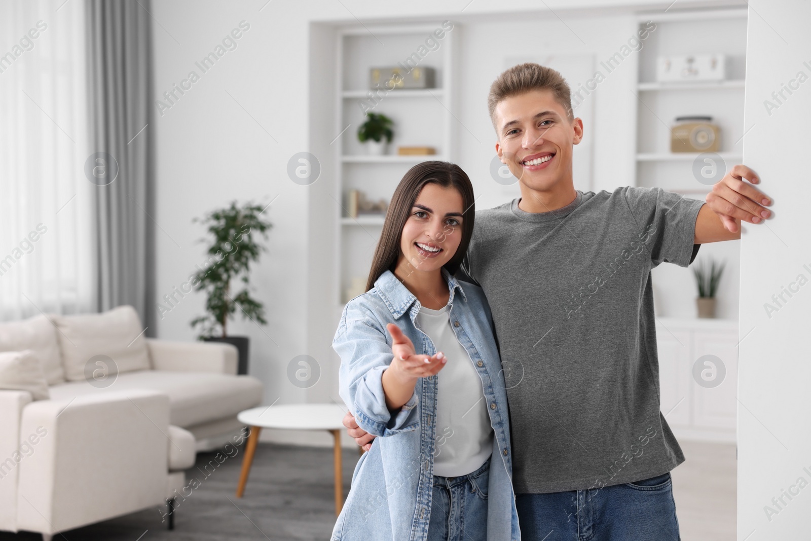 Photo of Happy couple welcoming near white wall at home, space for text. Invitation to come in room