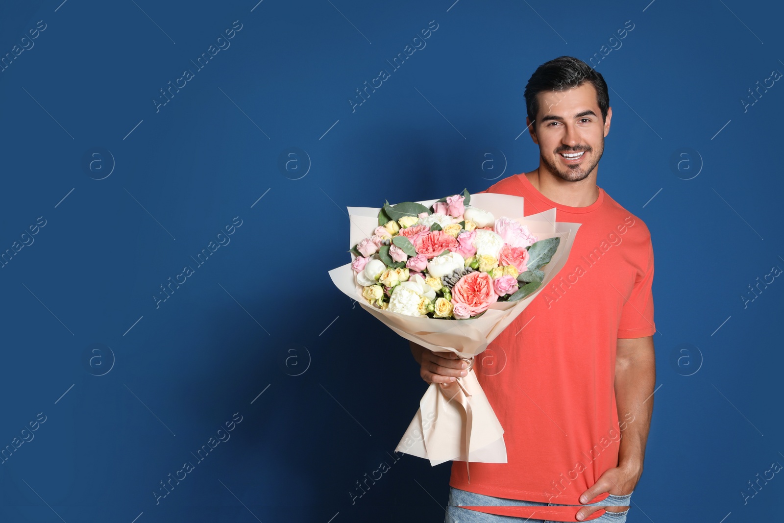 Photo of Young handsome man with beautiful flower bouquet on blue background, space for text