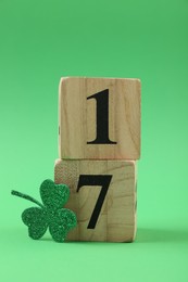 Photo of St. Patrick's day - 17th of March. Block calendar and decorative clover leaf on green background