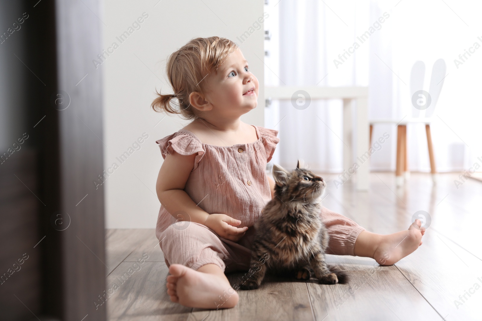 Photo of Cute little child with adorable pet on floor at home