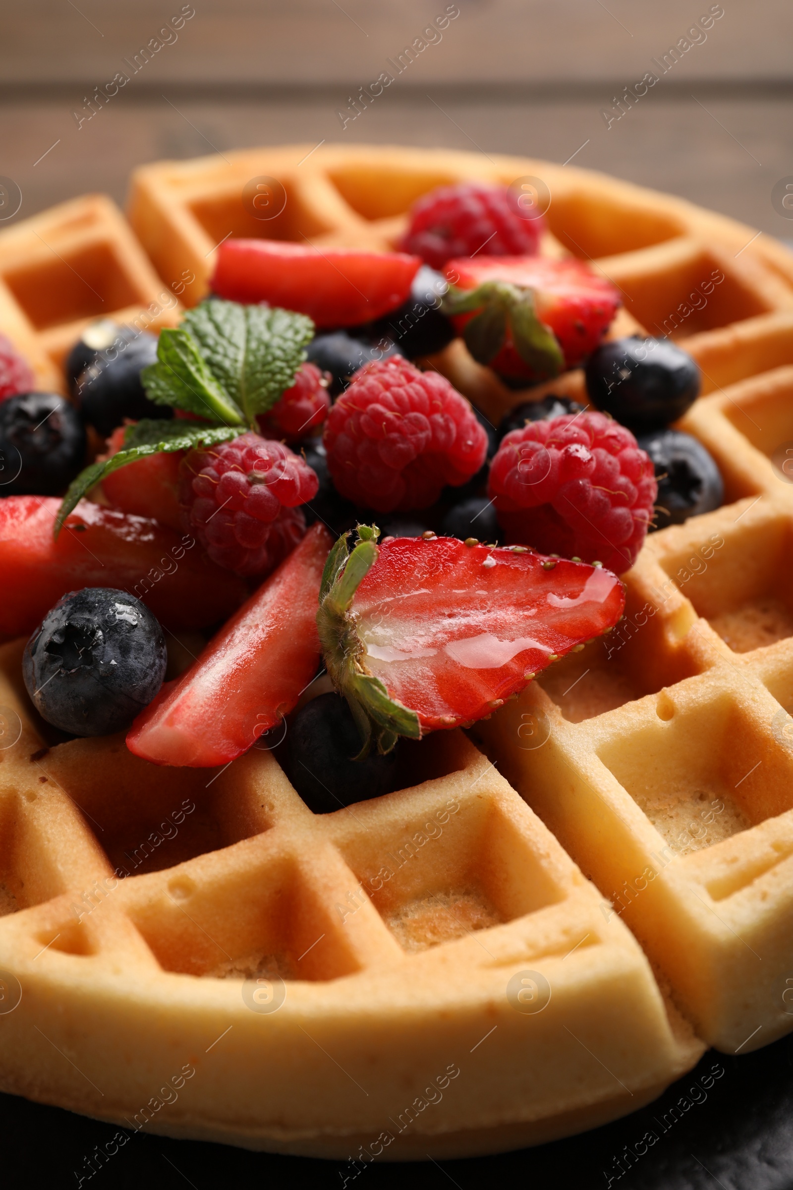 Photo of Tasty Belgian waffle with fresh berries on table, closeup