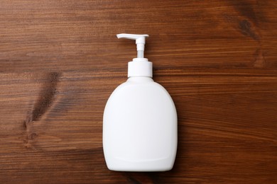 Dispenser of liquid soap on wooden table, top view