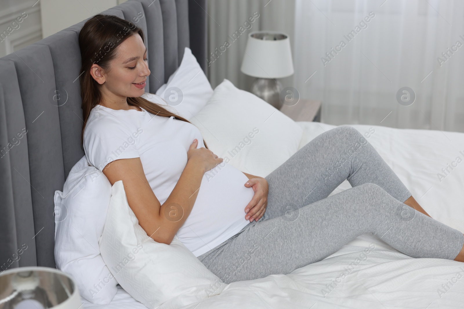 Photo of Beautiful pregnant woman with long hair in bedroom