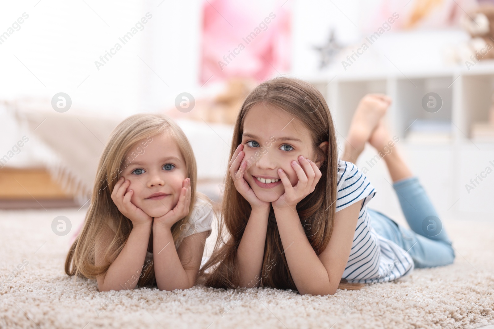 Photo of Cute little sisters on floor at home