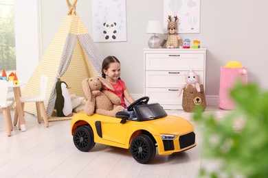 Photo of Adorable child with toy driving car in room at home