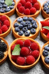 Photo of Tartlets with different fresh berries on light grey table, above view. Delicious dessert