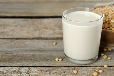 Photo of Glass with fresh soy milk and grains on wooden table. Space for text