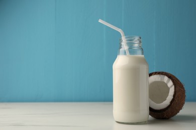 Glass bottle of delicious vegan milk and coconut on white marble table. Space for text